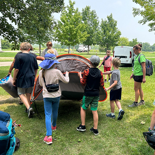 A group of kids carrying a tent