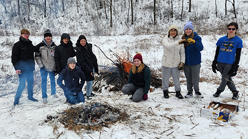 students standing around a fire in a snowy landscape